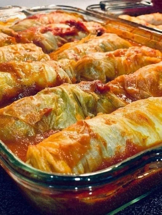 Plnené kapustné závitky servírované na tanieri s bylinkami.